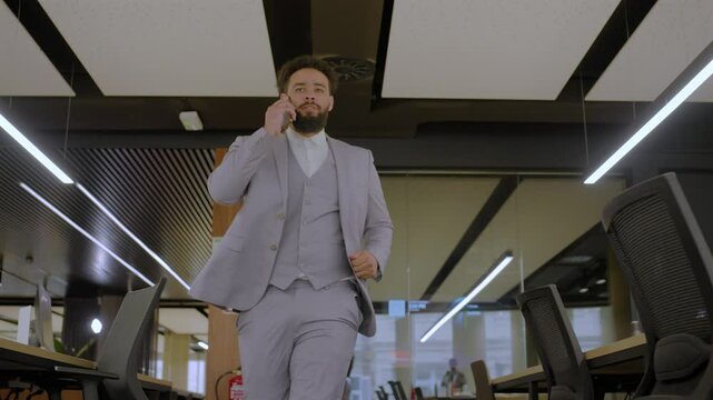 Welldressed African American businessman happily strides through empty coworking space, engaged in a phone conversation highlights fun and professionalism, got promoted concept. Dancing Businessmen 