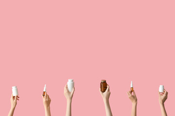 Hands with nasal sprays and pills on pink background