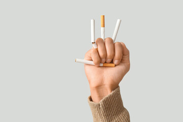 Female fist with broken cigarettes on grey background, closeup. Stop smoking concept