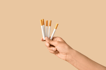 Female hand with cigarettes on beige background. Stop smoking concept