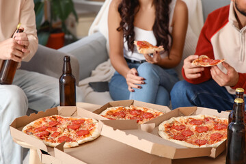 Friends with beer eating pepperoni pizza at home, closeup