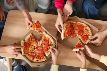 Group of friends taking slices of pepperoni pizza from table at home party, top view