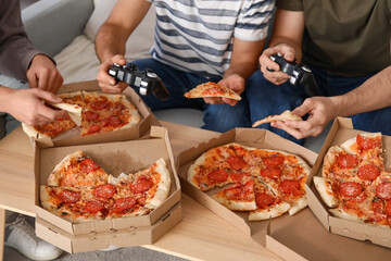 Male friends with pepperoni pizza playing video game at home, closeup © Pixel-Shot