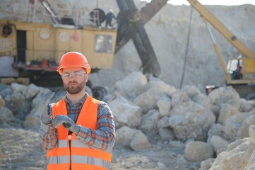 Extraction of stone. Male worker next to stone quarry. Engineer at construction site