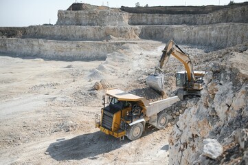 Heavy mining truck and excavator, close-up, against the background of the panorama of a limestone quarry