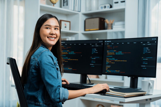 Young Asian in IT developer looking at camera to present with online information on pc with coding program data application, wearing jeans shirt. surround by safety analysis two screens. Stratagem.