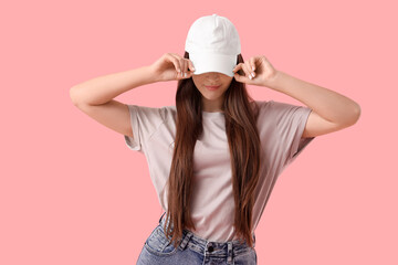 Young woman in cap on pink background