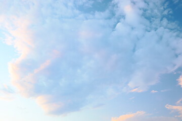 Beautiful clouds reflecting soft hues in the evening sky above a serene landscape during sunset...