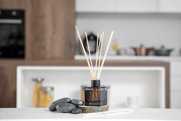Reed diffuser with spa stones on table in kitchen, closeup