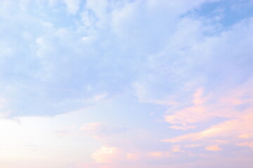 Soft pastel clouds fill the sky at sunset over a serene horizon during a tranquil evening in nature.