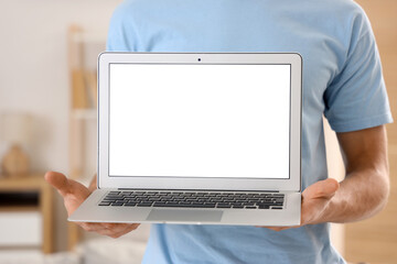 Young man with blank laptop at home, closeup