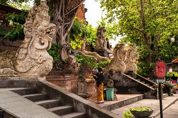 Bali, Indonesia: Traditional Balinese temple adorned with intricate dragon statues amidst lush...
