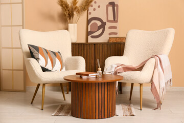 Interior of living room with armchairs, coffee table and commode near brown wall