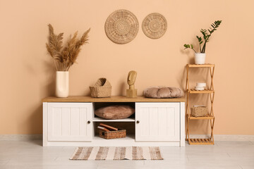 Interior of living room with shelving unit and home decor on commode near brown wall