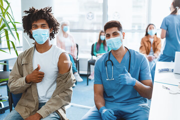 Safety, Mass flu Vaccination. Vaccinated African American Guy Patient And Medical Worker Gesturing...