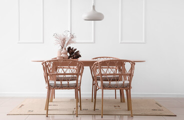 Vases with dried flowers on dining table in light room interior