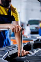 Repairman in car service uses torque wrench to tighten bolts after replacing steering mechanism. Knowledgeable auto repair shop worker uses professional tools to fix customer automobile