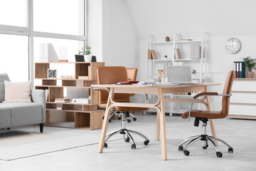 Interior of light office with desk and shelf units