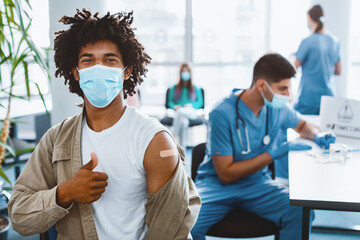 Successful flu Vaccination. Vaccinated African American Guy In Face Mask Showing Thumb Up Gesture...