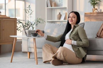 Young pregnant woman taking dried prune from table at home