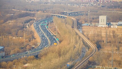 Urban highway and railway intersecting amidst a winter landscape in a suburban area