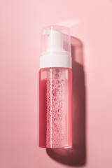 Mockup of transparent Jar with foaming liquid inside dispenser for soap, lotion, beauty care products on pink background