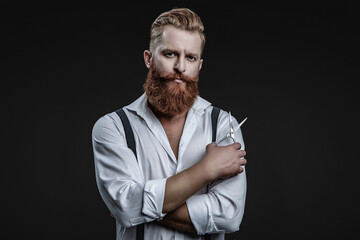 Bearded Caucasian man hairdresser in hair salon. Hairstylist working in a hair salon. Barber using...