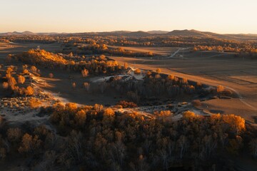 Scenic autumn landscape at dusk with rolling hills and vibrant foliage in a tranquil rural setting
