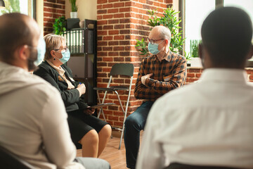 Retired female psychiatrist holding clipboard and advising elderly man at aa group meeting. Senior...
