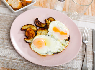 Image of a appetizing fried eggs, cooked with sliced roasted eggplant