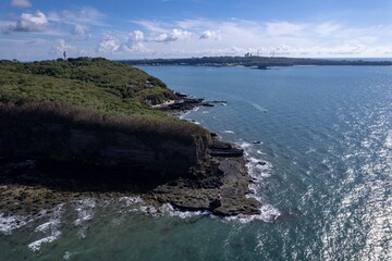 Stunning coastal view showcasing rocky cliffs and the blue sea under a clear sky near a city