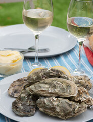 Plate with fresh live oysters with citron, bread, butter and white wine served at restaurant in oyster-farming village, Arcachon bay, Gujan-Mestras port, France