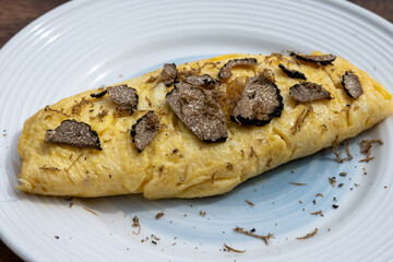French omelette with mushrooms, fresh farmers eggs and black summer truffle mushroom in pieces for making truffle dishes with tasty aroma