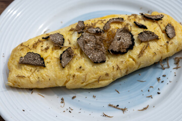 French omelette with mushrooms, fresh farmers eggs and black summer truffle mushroom in pieces for making truffle dishes with tasty aroma