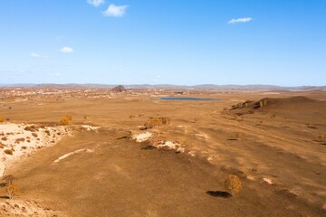 Expansive desert landscape with a distant water body under clear blue skies during daylight hours