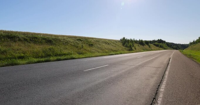an empty road against a blue sky background, a highway in a rural area with a blue sky and green grass on the side of the road