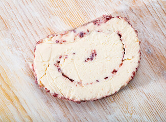 Slice of soft cheese with cranberries and pasteurized milk on wooden surface..