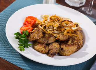 Tasty rabbit liver fried with onion garnished with fresh parsley and blanched cherry tomatoes