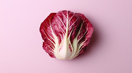 Obraz premium Red cabbage resting on a pastel pink background showcasing its vibrant leaves and unique shape for a minimalist aesthetic