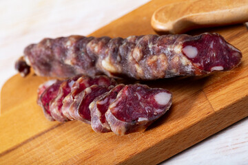 Sliced French dry sausage on wooden cutting board