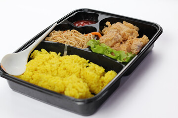 Nasi kuning or yellow rice in a bento box isolated on white background. Yellow Rice is an Indonesian fragrant rice dish cooked with coconut milk and turmeric.