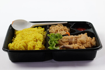 Nasi kuning or yellow rice in a bento box isolated on white background. Yellow Rice is an Indonesian fragrant rice dish cooked with coconut milk and turmeric.