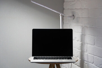 Macbook on a wooden table against the background of gray minimalist walls of the room