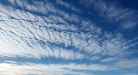 Midday sky with crisp white cirrostratus clouds forming thin, wispy patterns across the blue expanse