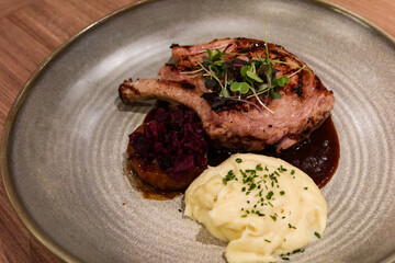 close up of grilled pork rack with mashed potato on the side on a big plate dish