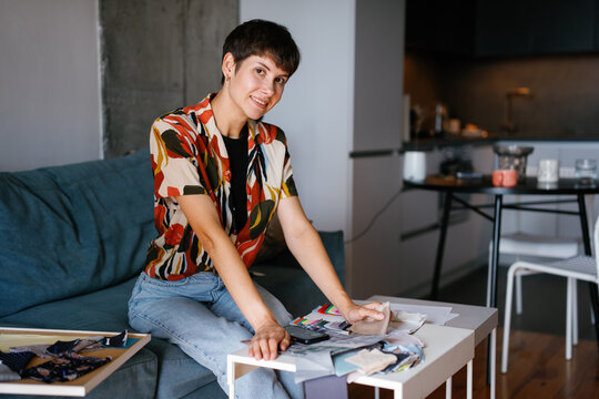Female designer looking at camera and choosing colors for clothes