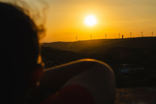 Sunset view with wind turbines from a contemplative perspective.