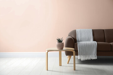 Sofa in mocha mousse shade and house plant indoors. Interior with trendy color of 2025 year