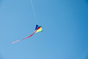 One colorful kite flying in blue sky