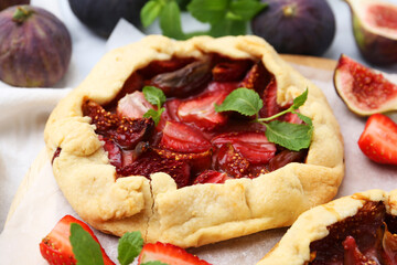 Tasty galette with strawberries, figs and mint on table, closeup